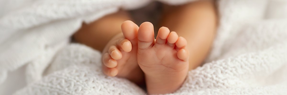 Adorable baby feet covered in a white blanket, maternity and bab Adorable baby feet covered in a white blanket, maternity and bab